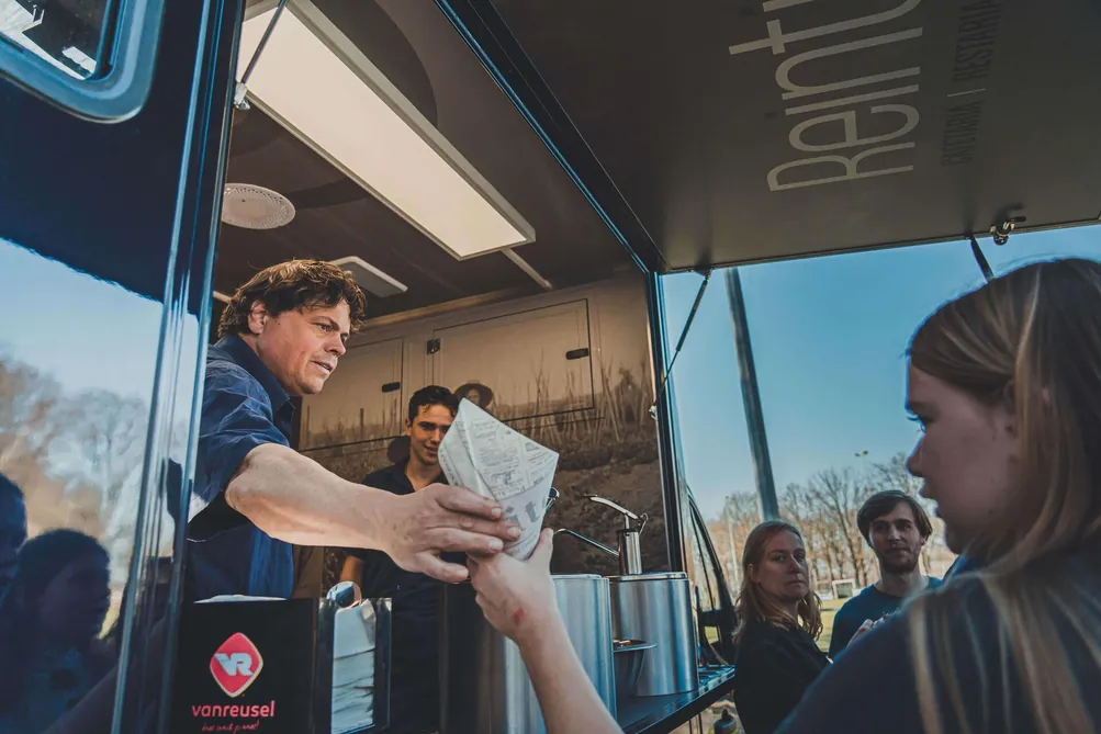 Klant krijgt verse friet aan het uitgifteluik van Frietwagen Reintje